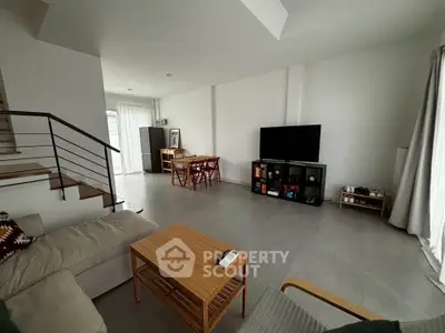 Spacious modern living room with sleek furniture and large TV, perfect for relaxation and entertainment.