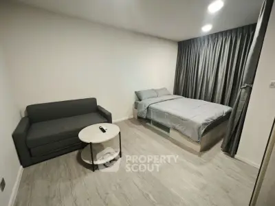 Modern studio apartment with cozy bed and sleek sofa in minimalist design.