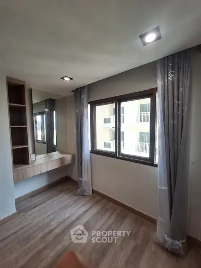 Bright bedroom with large windows and built-in vanity in modern apartment