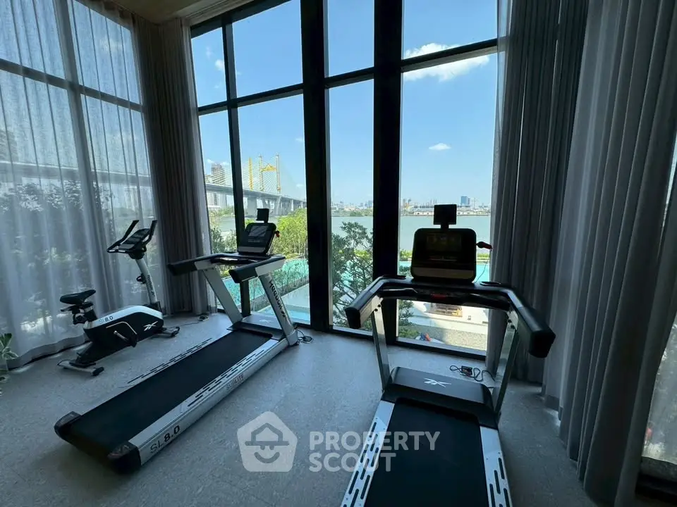 Luxurious gym with modern equipment and stunning city view through large windows.