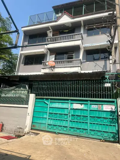 Charming multi-story building with gated entrance and balconies in urban setting.