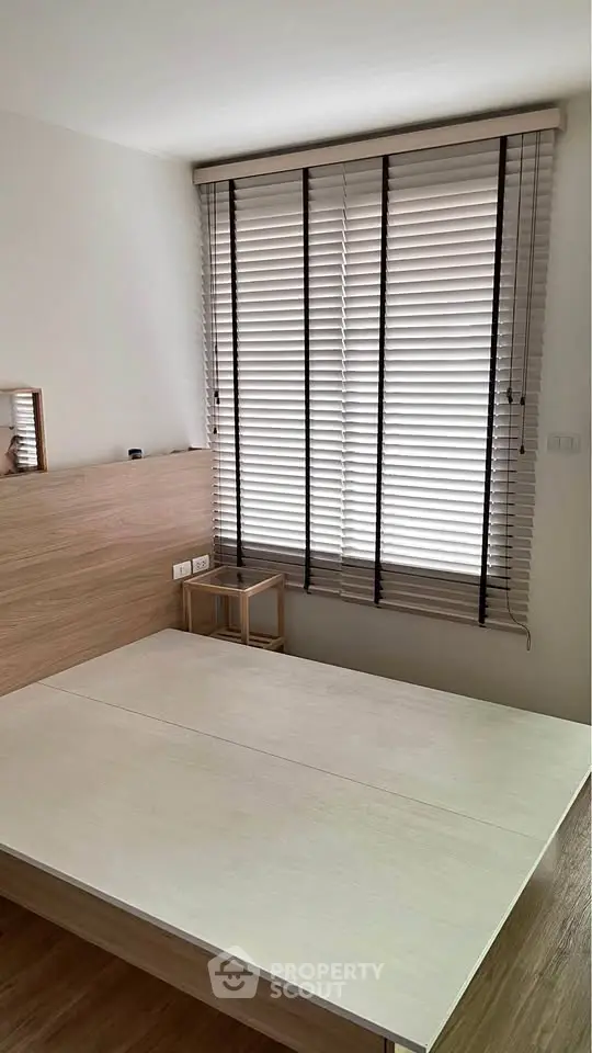 Modern bedroom with wooden accents and large window blinds