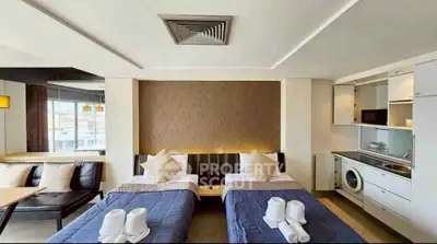 Modern studio apartment with twin beds, kitchenette, and city view.