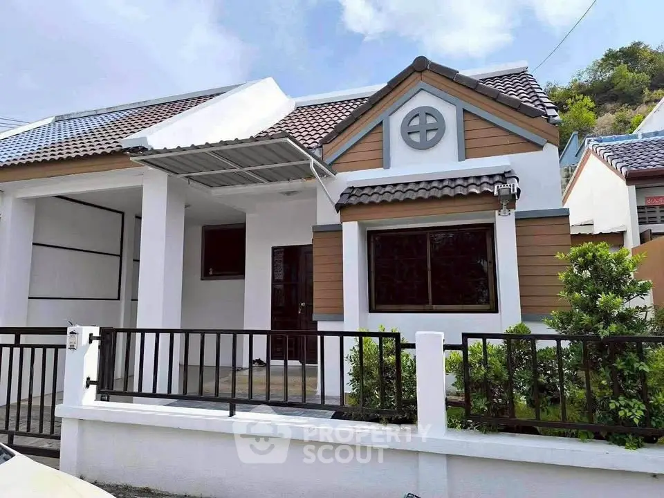 Charming single-story house with modern facade and fenced front yard.