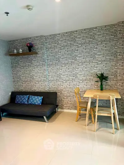 Modern living room with stylish brick wall, cozy sofa, and dining table in a bright apartment.