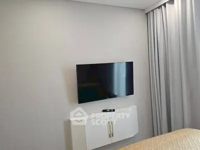 Modern bedroom with wall-mounted TV and sleek white cabinet