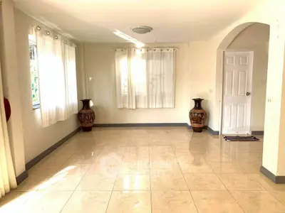 Spacious empty living room with tiled floor and decorative vases, perfect for customization.