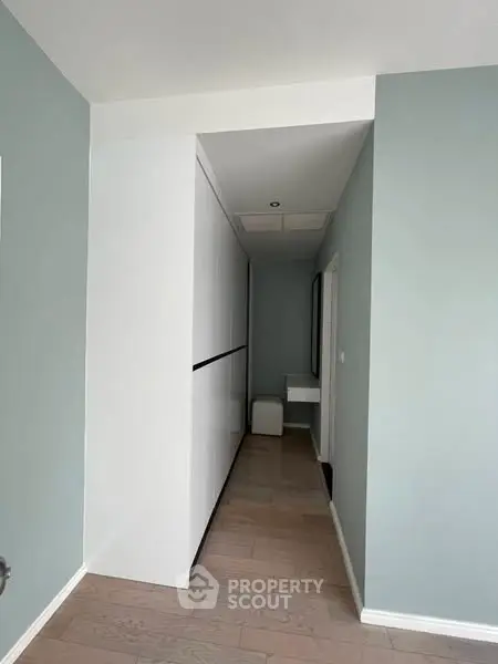 Modern hallway with sleek white storage and light wood flooring