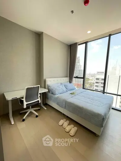 Modern bedroom with city view, featuring a cozy bed and workspace, ideal for urban living.