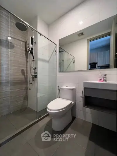 Modern bathroom with glass shower and sleek fixtures in contemporary apartment.