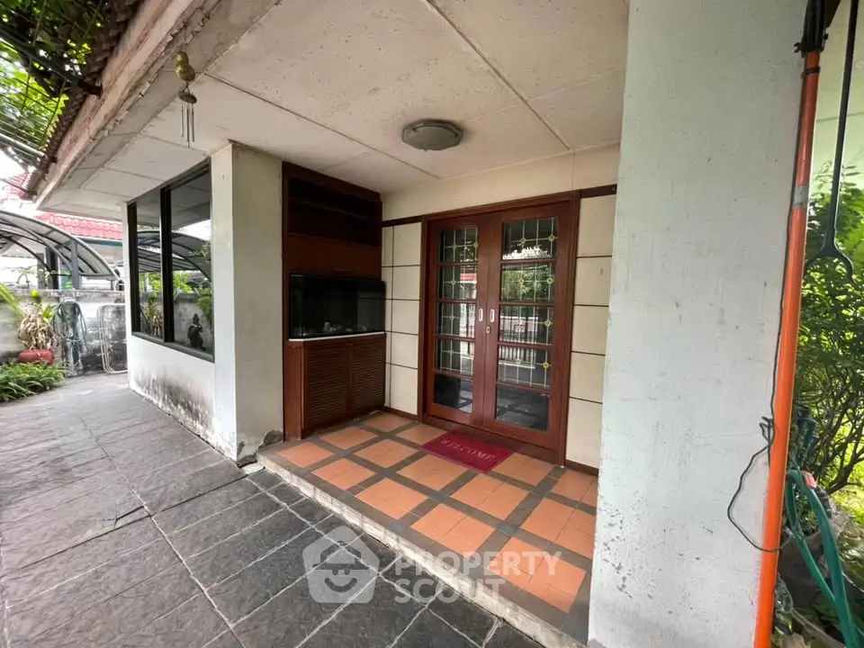 Charming entrance with tiled patio and lush greenery, perfect for welcoming guests.