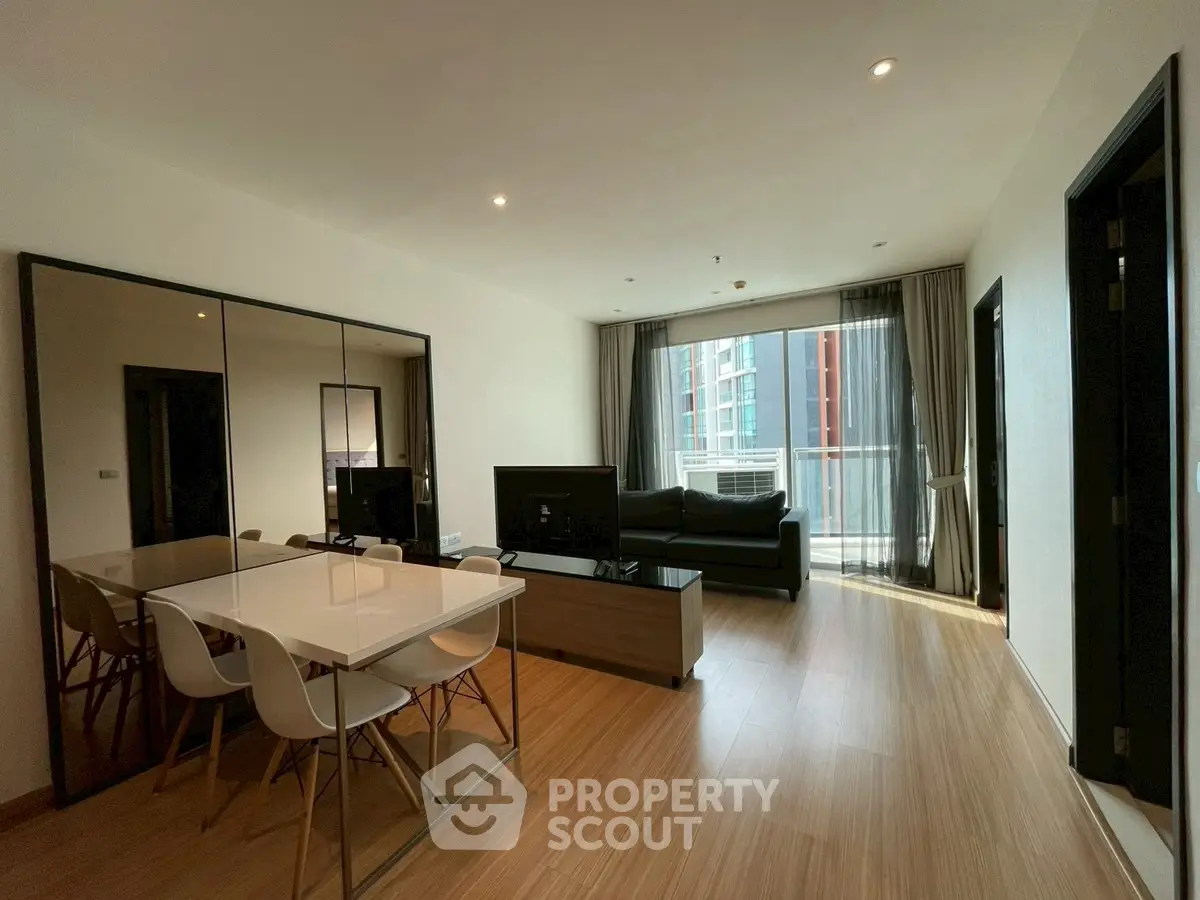 Spacious modern living room with dining area and balcony view in urban apartment.
