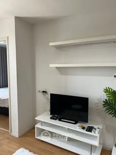 Modern living room with sleek TV stand and floating shelves, adjacent to a cozy bedroom.