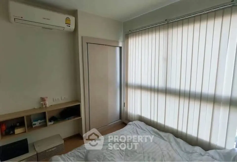 Cozy bedroom with air conditioning and natural light through vertical blinds.