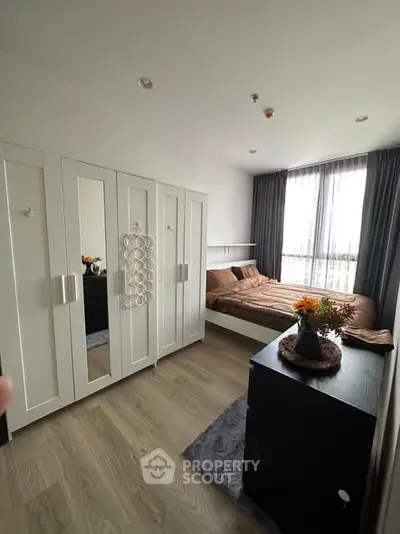 Modern bedroom with stylish decor and ample natural light, featuring a cozy bed and sleek wardrobe.
