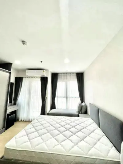 Spacious bedroom with modern furnishings and large windows for natural light.
