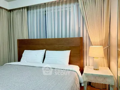 Cozy bedroom with elegant curtains and warm lighting, featuring a comfortable bed and stylish wooden headboard.