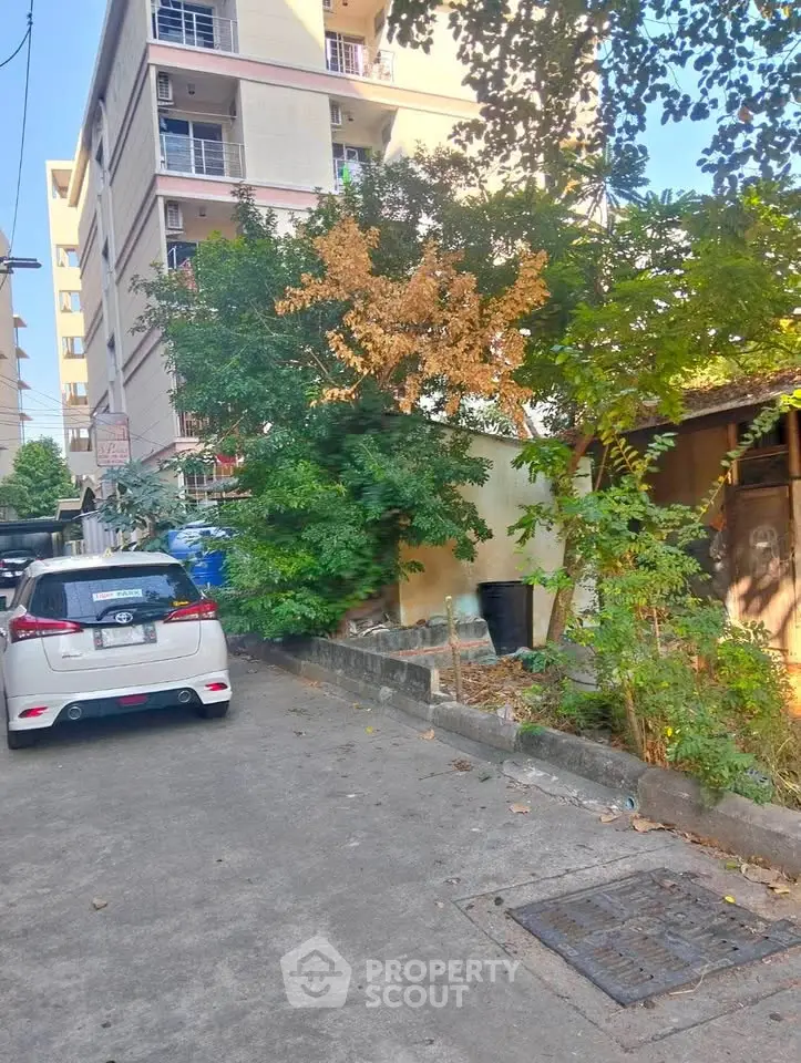 Urban residential street with apartment buildings and parked cars, showcasing city living environment.