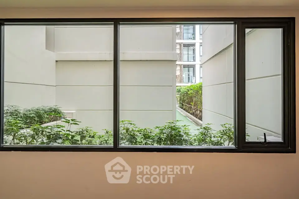 Modern apartment window view with lush greenery and building exterior