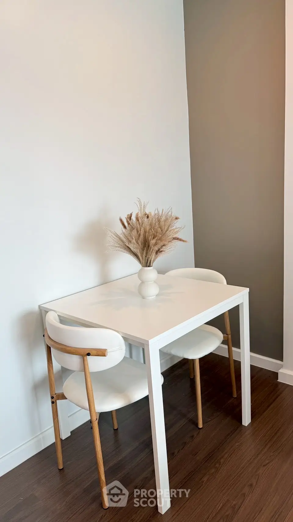 Modern dining nook with white table and chairs, featuring minimalist decor.