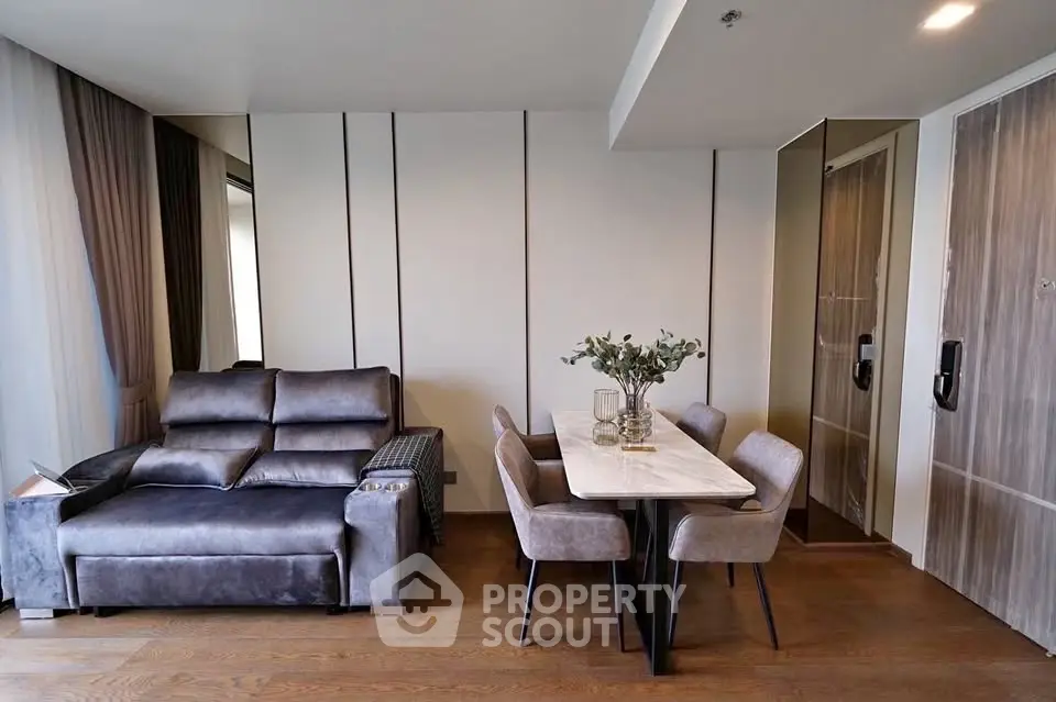 Modern living room with stylish dining area and plush gray sofa, featuring elegant decor and wooden flooring.