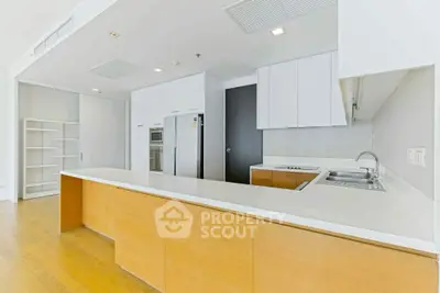 Modern kitchen with sleek white cabinets and wooden accents, featuring built-in appliances and ample counter space.