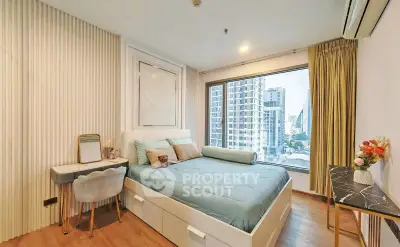 Modern bedroom with large window offering city view, stylish decor, and cozy furnishings.