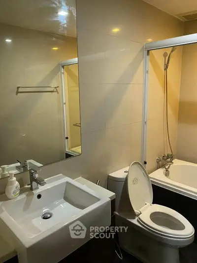 Modern bathroom with sleek sink, toilet, and bathtub in contemporary apartment.
