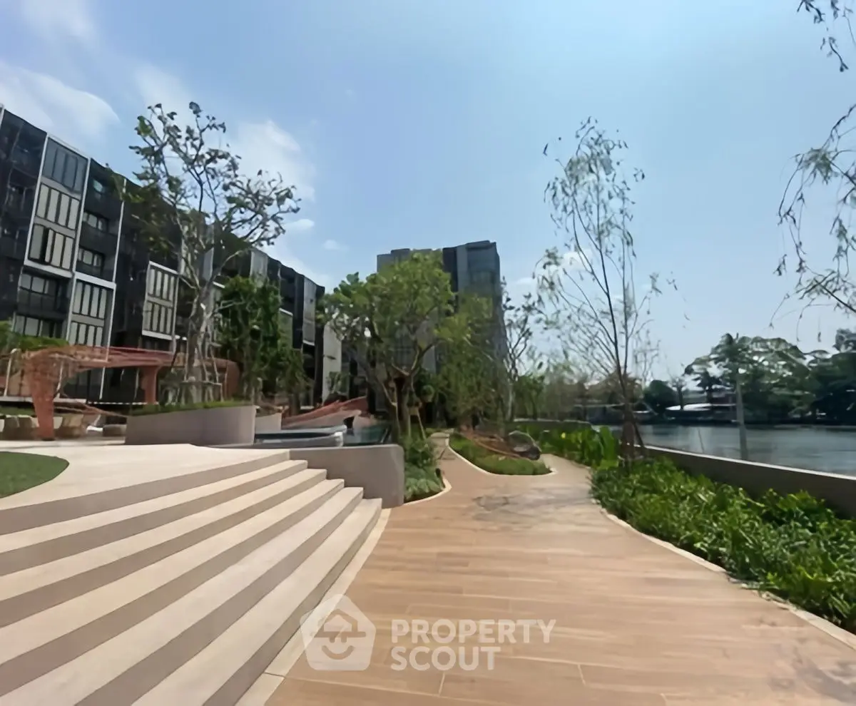 Luxurious riverside apartment complex with modern architecture and lush landscaping.