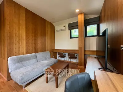 Modern living room with wooden walls, cozy sofa, and large TV, perfect for relaxation and entertainment.