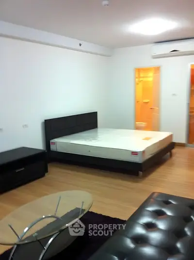 Spacious modern bedroom with sleek furniture and wooden flooring in a stylish apartment.
