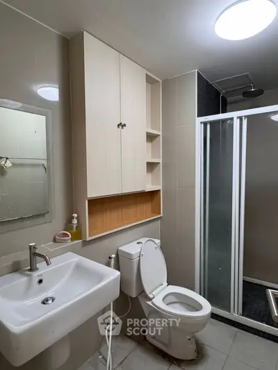Modern bathroom with sleek fixtures and shower enclosure in contemporary apartment.