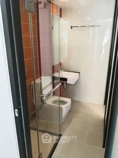 Modern bathroom with glass shower, sleek sink, and contemporary design.