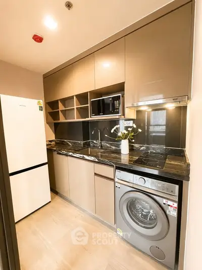 Modern kitchen with sleek cabinetry, marble countertops, and built-in appliances in a compact layout.