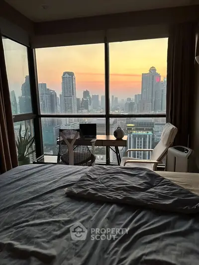 Stunning city view from modern bedroom with workspace setup at sunset.