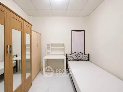 Minimalist bedroom with single bed, wardrobe, and study desk in a compact space.
