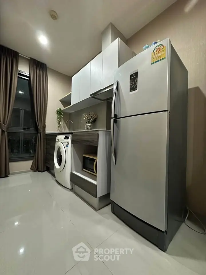 Modern kitchen with sleek appliances including fridge, washing machine, and microwave in stylish apartment.
