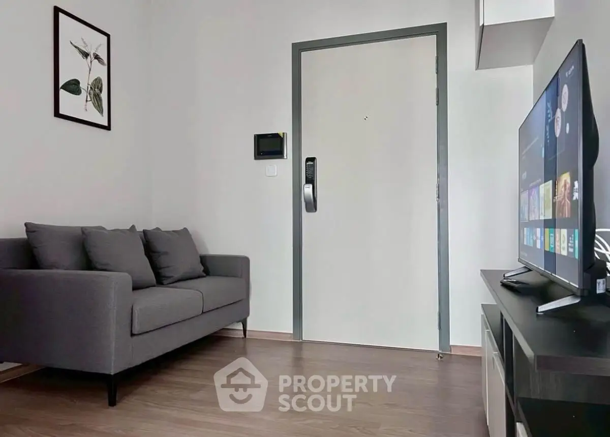 Modern living room with sleek gray sofa and wall-mounted TV, perfect for cozy relaxation.