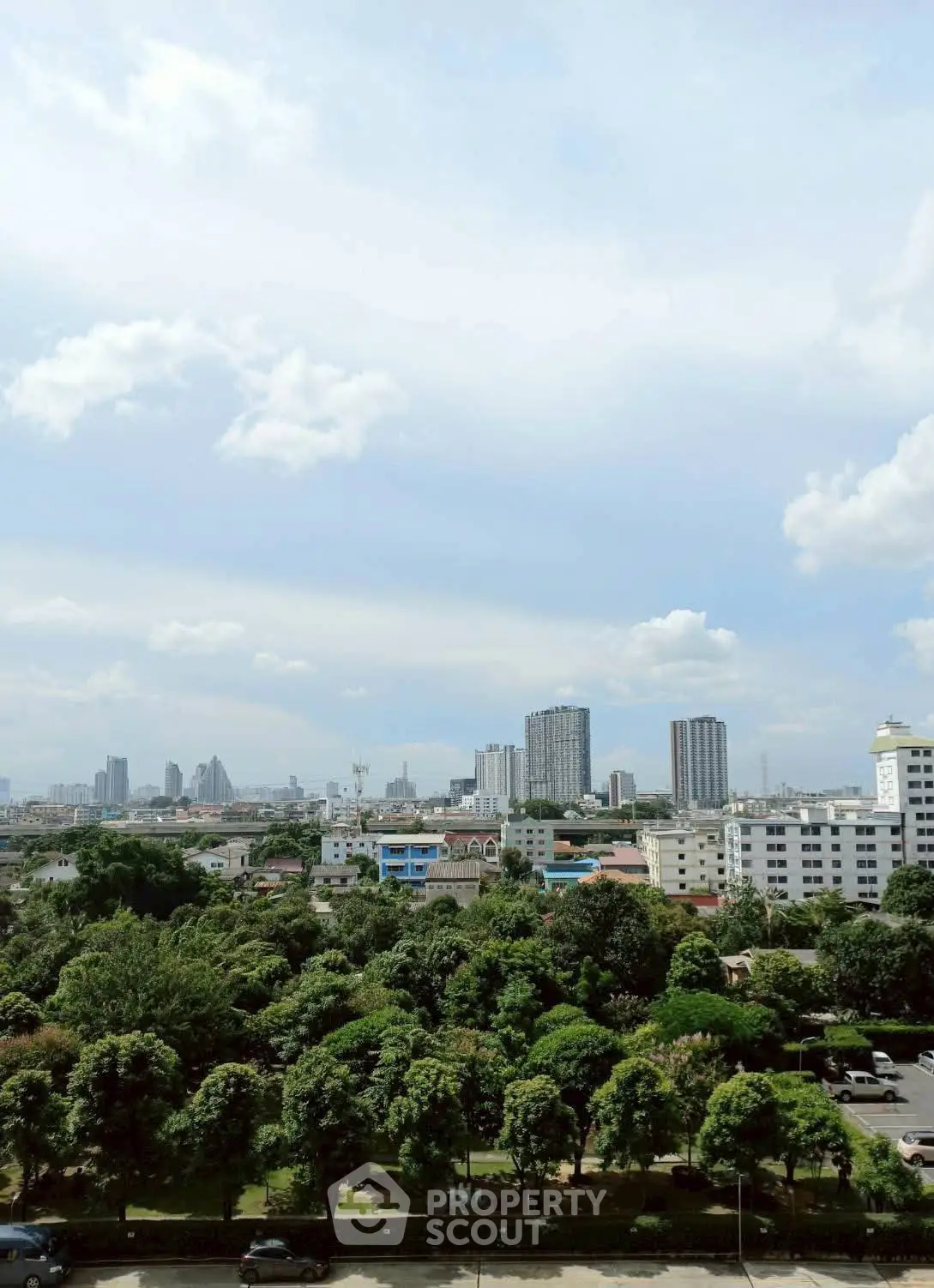 Stunning cityscape view from a high-rise building showcasing lush greenery and urban skyline.