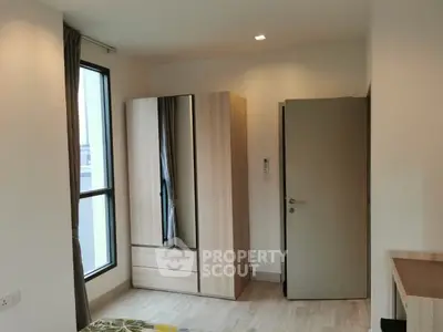 Modern bedroom with large window and sleek wardrobe in a stylish apartment.