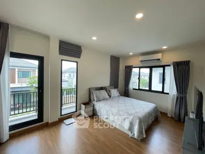 Spacious bedroom with modern decor and large windows offering natural light.