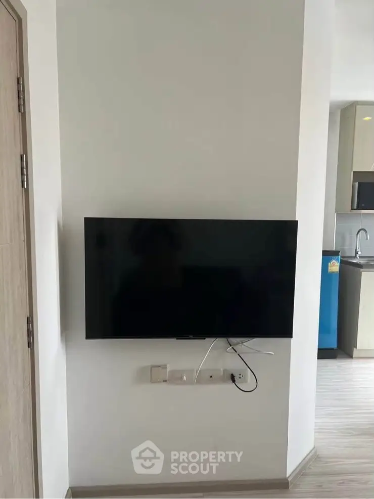 Modern apartment interior with wall-mounted TV and sleek kitchen design.