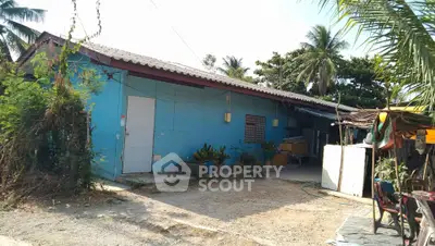 Charming rural blue house with lush greenery and spacious outdoor area.