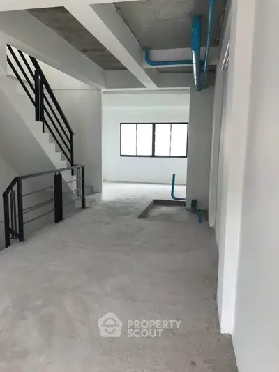 Spacious unfinished interior with modern staircase and large windows, ideal for customization.