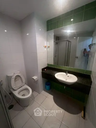 Modern bathroom with sleek design, featuring a shower, toilet, and stylish sink area.