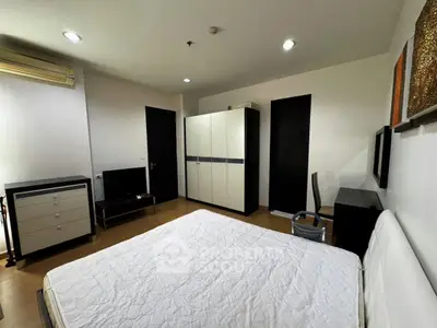 Spacious bedroom with modern furniture and ample storage in a stylish apartment.