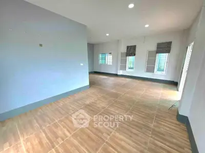 Spacious empty room with wooden flooring and large windows, ideal for customization.