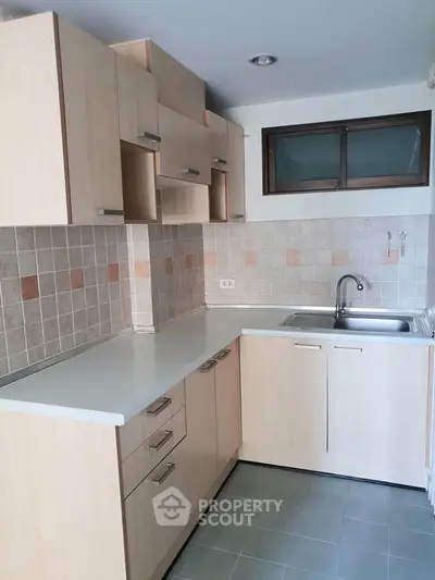 Modern kitchen with light wood cabinets and tiled backsplash