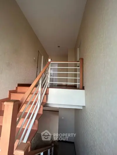 Modern staircase with wooden steps and sleek railing in a contemporary home interior.