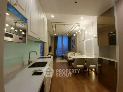 Modern open-layout kitchen and living room with elegant lighting and wooden flooring.